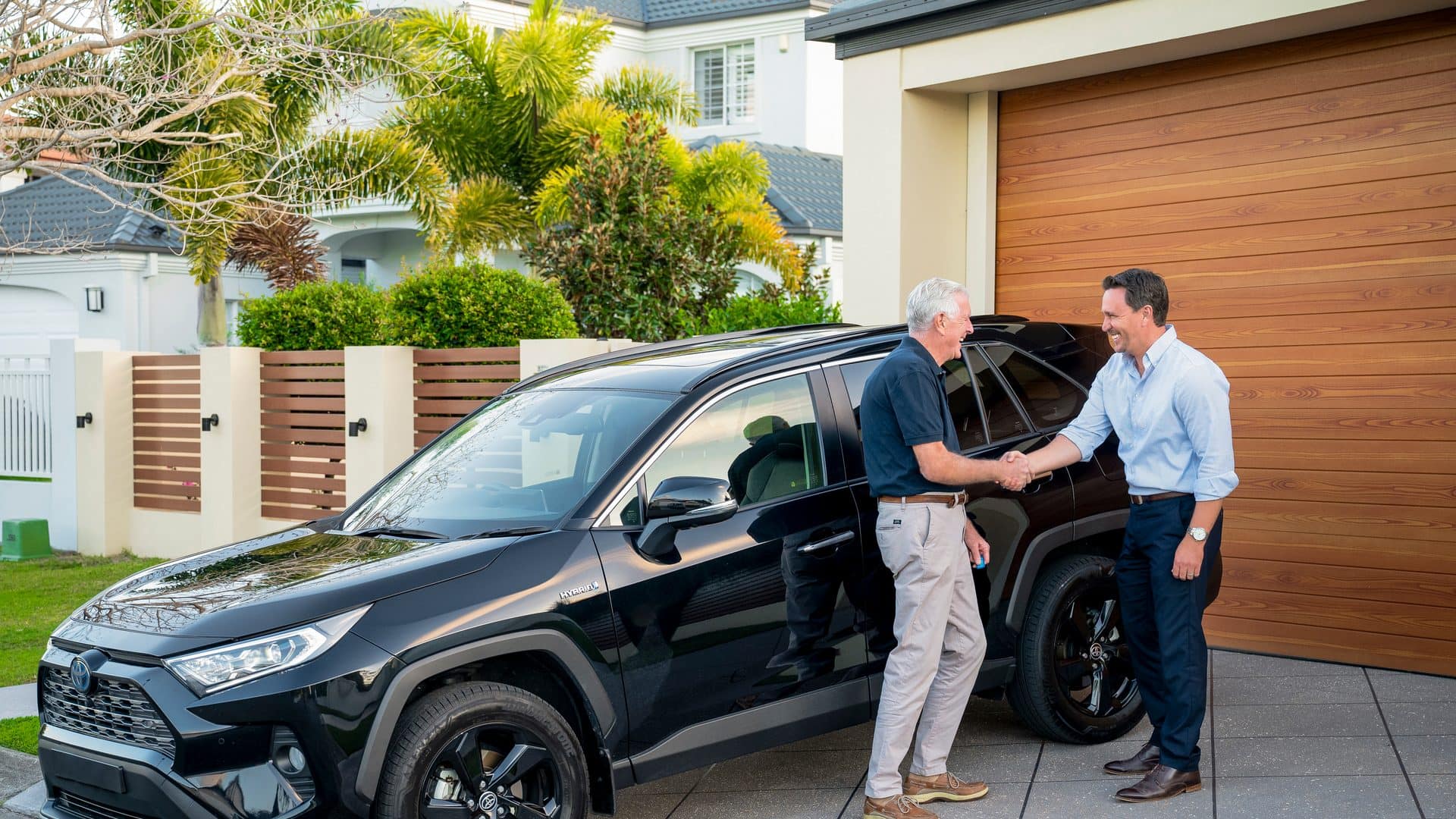 A customer shaking hands with Adam Hall beside the car he has just bought